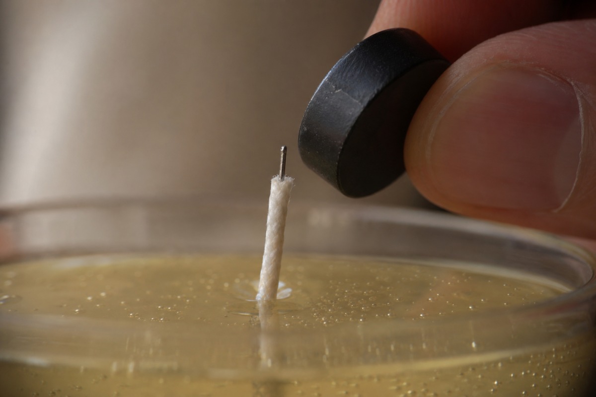 Detail van een uitgetrokken lont met een dunne metalen kern, met een kleine magneet vlak bij die metalen kern
